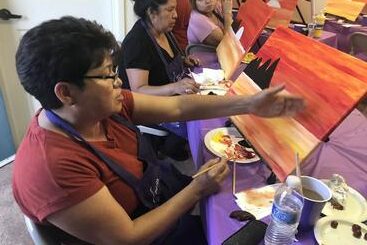 A group of people sitting at a table painting.