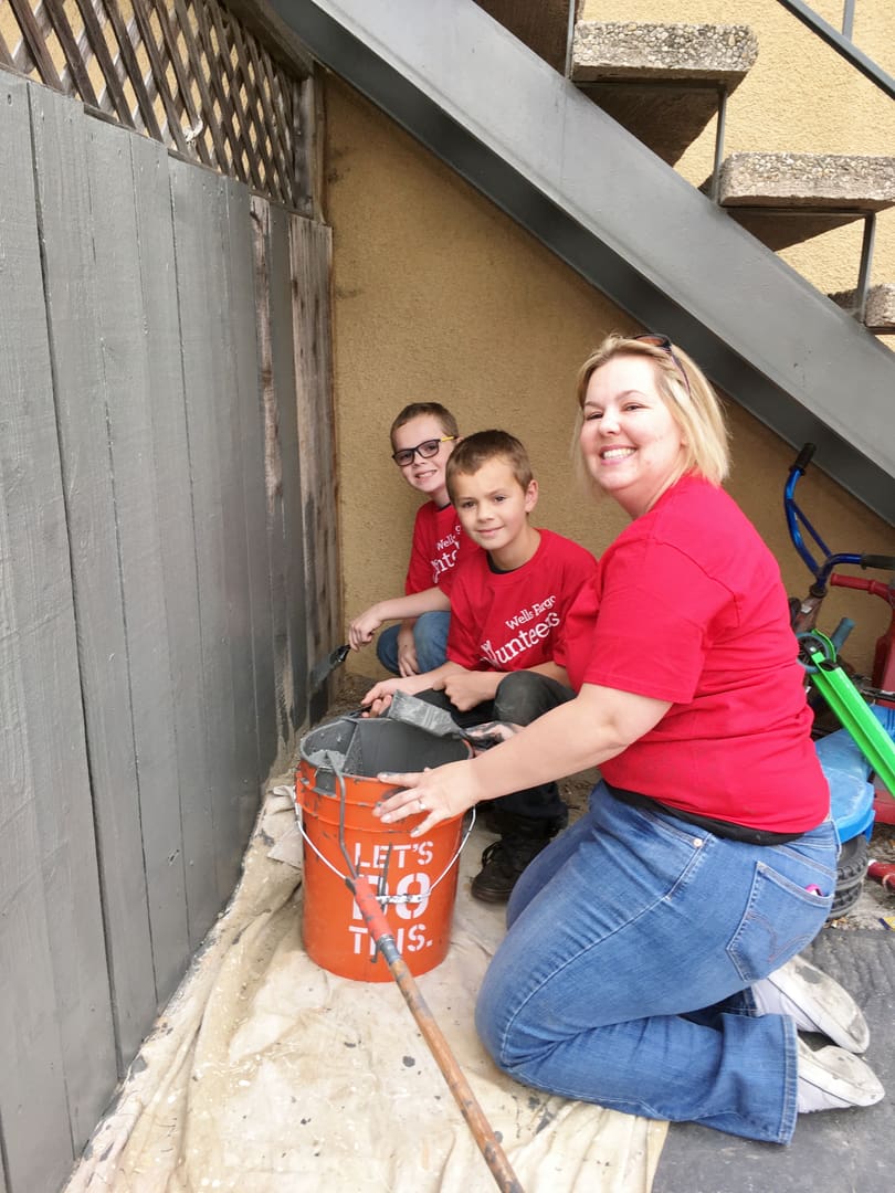 A woman and two boys are painting the wall.