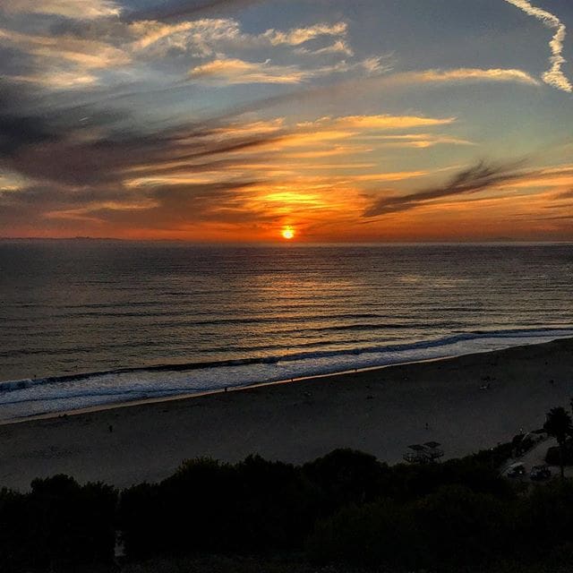 A sunset over the ocean with clouds in the sky.