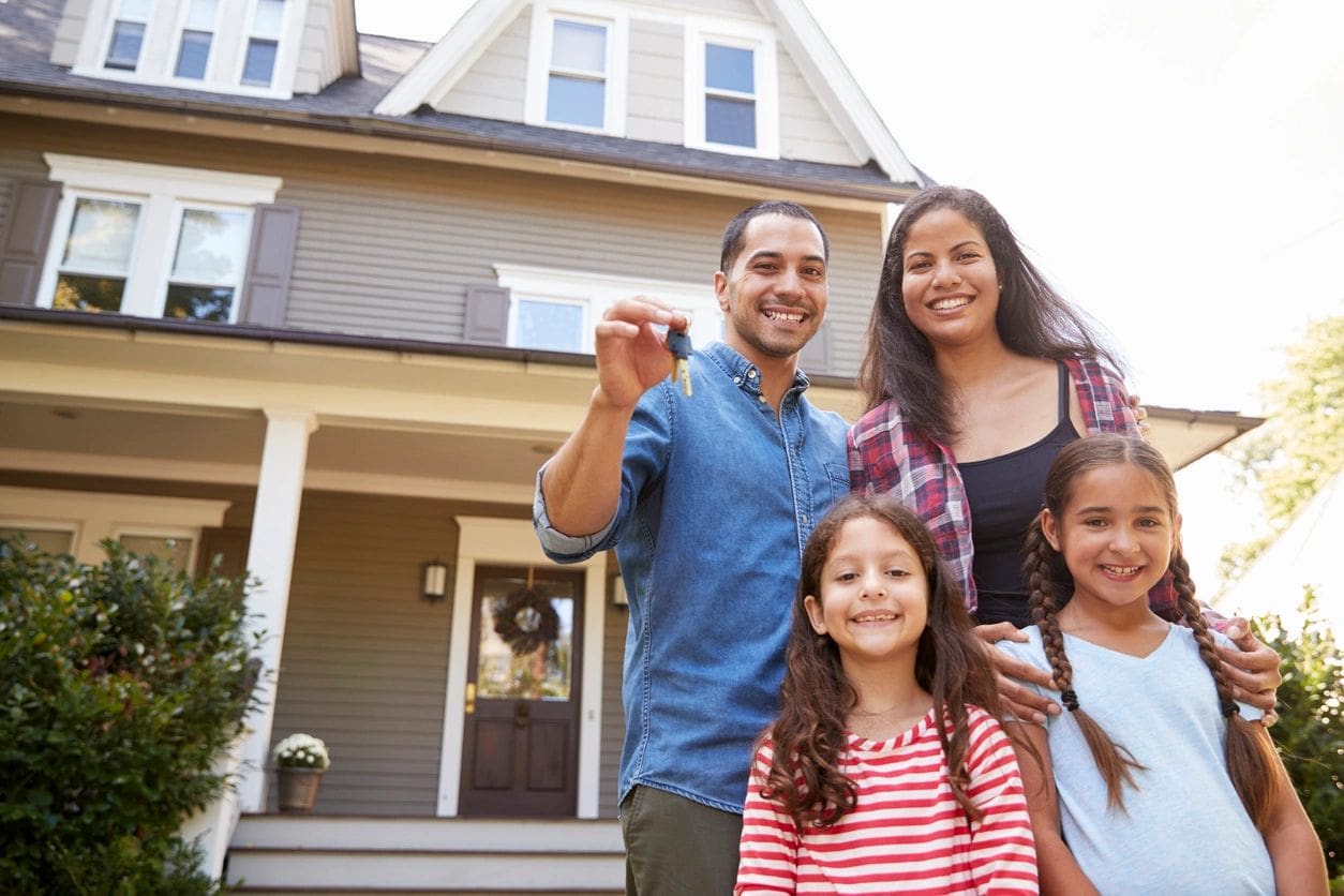 A family is standing in front of their home.