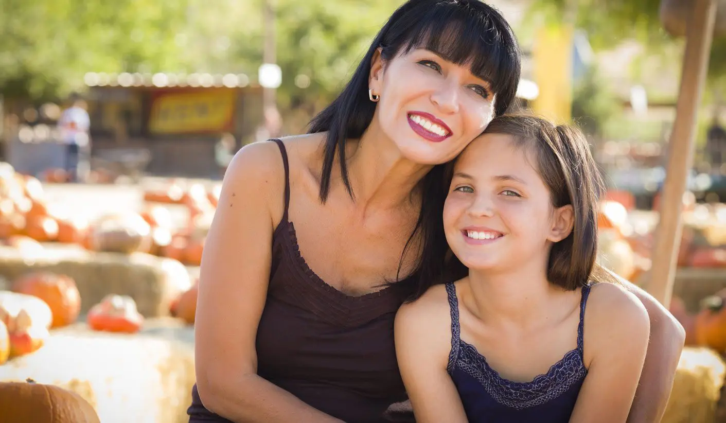 A woman and her daughter posing for the camera.