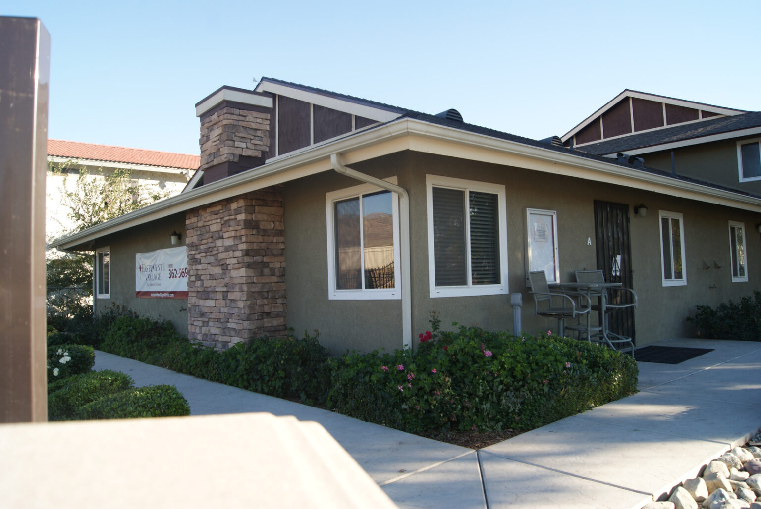 A house with a large lawn and bushes in front of it.