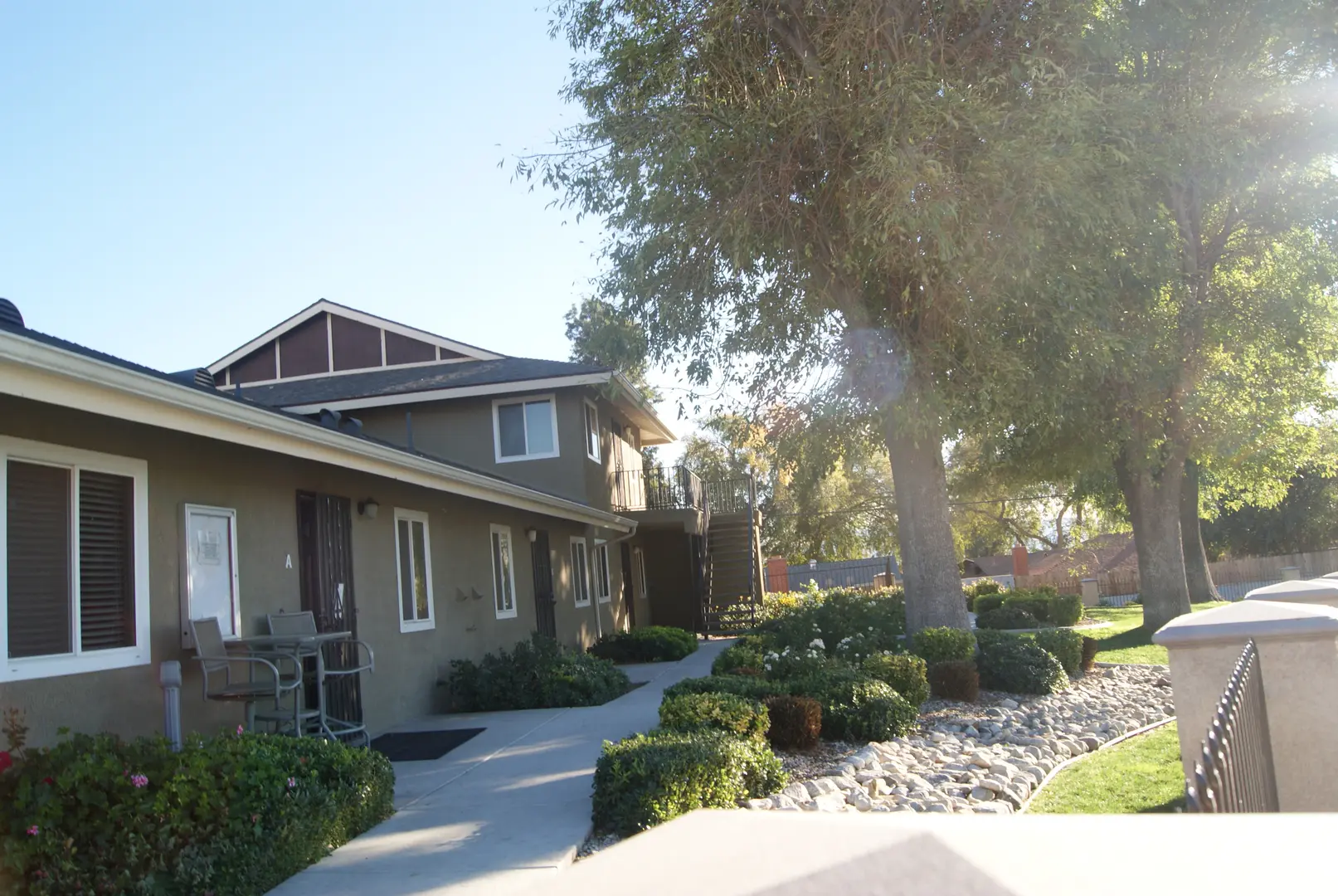 A house with a tree and bushes in the front yard.