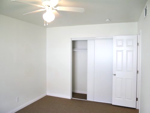 A bedroom with a ceiling fan and sliding doors.